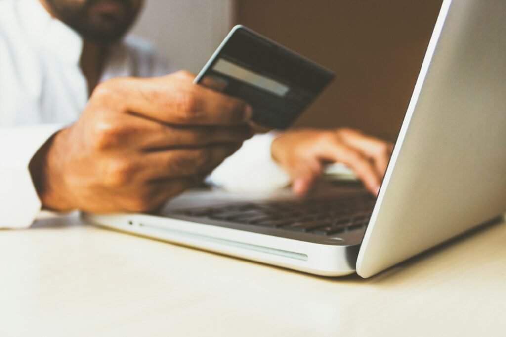 Person using a laptop while holding a bank card to pay a bill online